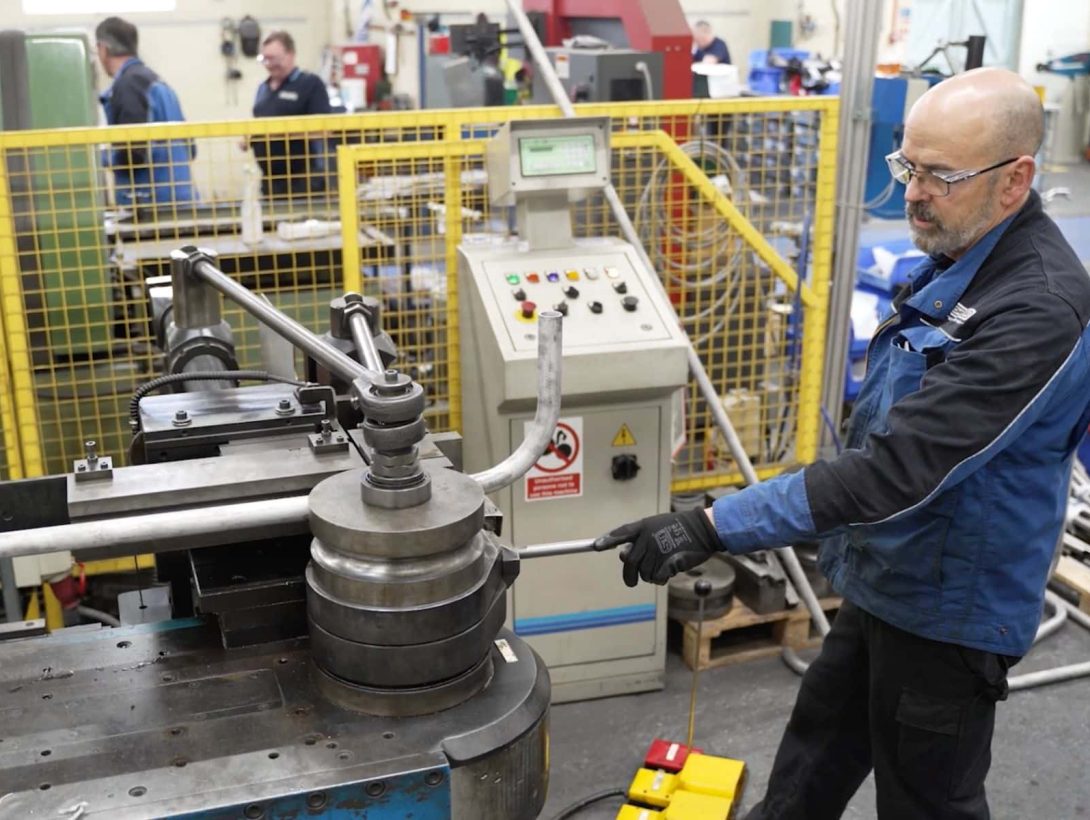 Operator performing CNC tube bending on industrial tube forming machine